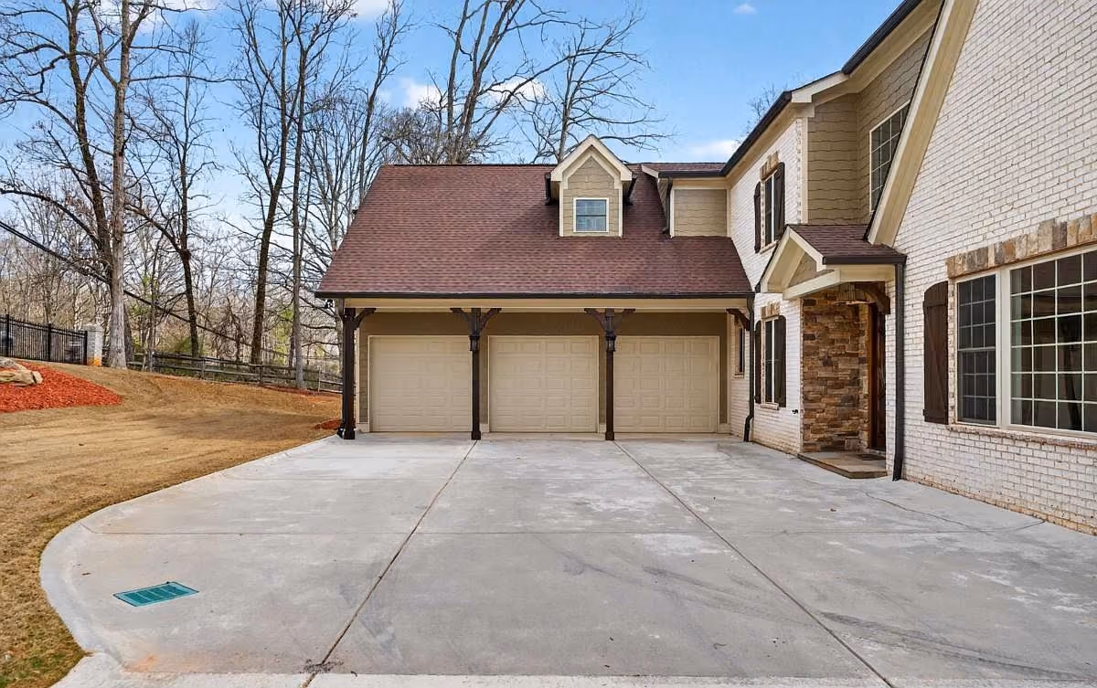 Clean concrete driveway running up to a three-car garage