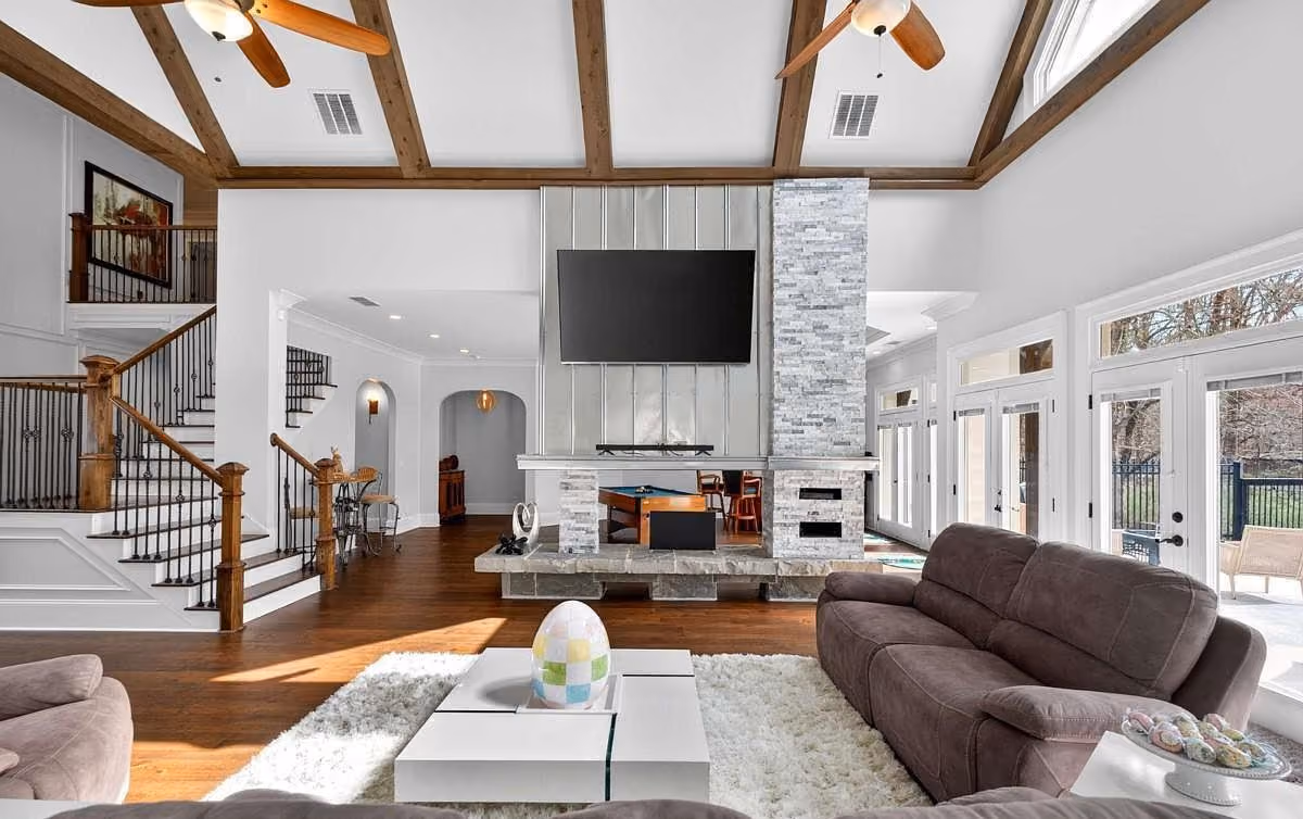 Great room with painted walls, exposed beams and a stone fireplace